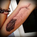 fehér és fekete toll tetoválás a lány karján