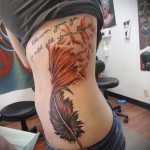 nagy toll és feliratok a lány oldalán - kész tetoválás a fotón