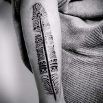 Maori minták egy tetoválásban, tollal a karján