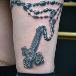 Fotó egy harisnyakötő tetoválásról és egy láncon lévő keresztről