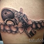 Fotó egy harisnyakötő tetoválásról és egy kis antik pisztolyról