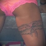 Fotó egy harisnyakötő tetoválásról egy lány rózsaszín bugyiban