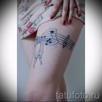 Fénykép egy tetováló harisnyakötőről, íjjal és jegyzetekkel - harisnyakötő, mint zenei könyv