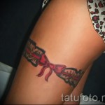 Fotó egy harisnyakötő tetoválásról, piros íjjal a lány lábán