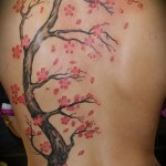 Tetoválás egy gyönyörű fiatal lány hátán, egy csokor virággal és egy fával - fotó