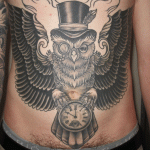 tetoválás a hasán - bagoly fejdíszben és órában