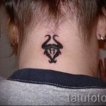 Fotó a Bika csillagjegy kész tetoválásáról - fekete szimbólum a lány tarkóján a haj alatt