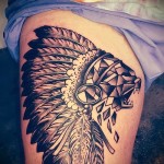 Állati vigyor tetoválás és fejdísz tollal - rajz egy nő lábára