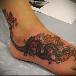 sárkány és virágok - tetoválás a lány lábának alsó részén
