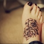 tetoválás három virággal a lány lábának alján