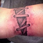 tetoválás a csuklón, amely durván összevarrt sebhez hasonlít