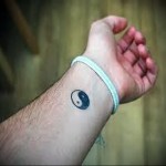 kis tetoválás yin-yang szimbólummal az ember csuklóján
