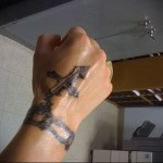 kereszt és karkötő tetoválás a kezében