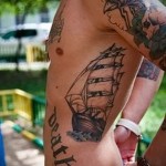 vitorlás és feliratok egy tetováláson egy férfi oldalán