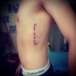 arab felirat egy tetováláson egy férfi oldalán