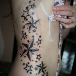 wiele gwiazdek różnej wielkości - kobiecy tatuaż na boku