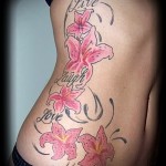kwiaty i napis (live for love) - kobiecy tatuaż na boku