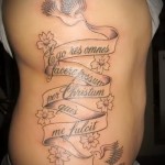 napis na wstążce i gołębie - kobiecy tatuaż z boku