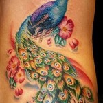 kolorowy paw i kwiaty - tatuaż na boku kobiety