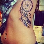 łapacz snów i dwa pióra - tatuaż z boku kobiety