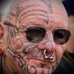 öregember piercingekkel és arc tetoválással