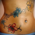 цветна татуировка с цветя в долната част на корема на момичето