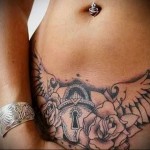 татуировка на замък и крила в долната част на корема на момиче