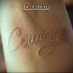 tatuaż z białym napisem na ramieniu