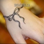 bransoletka i kokardka - tatuaż na ramię