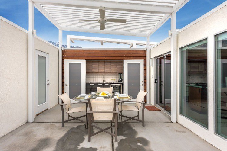 moderný dizajn bytu s bielou krytou terasou s ventilátorom a posuvnými sklenenými dverami