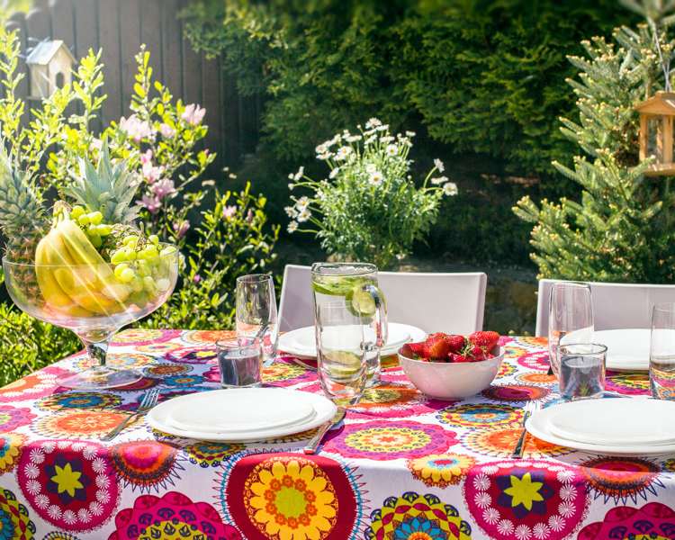 žiarivo vzorovaný obrus a biele taniere Dekorácia stola koncom leta, záhrada s obrusom s pestrými vzormi