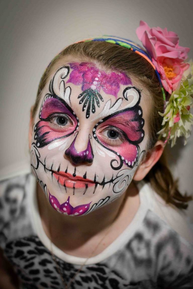 Halloween nápad na líčenie namaľuje ružový motýľ okolo očí a kvety na čelo