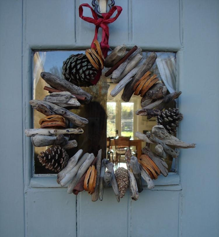 Veniec do dverí vyrobený z naplaveného dreva, čapov a rozkývaných plátkov pomaranča turkranz-prírodné-materiály-drotárstvo-dekorácia-jeseň-zima-suché-oranžové-plátky-naplavené kužele