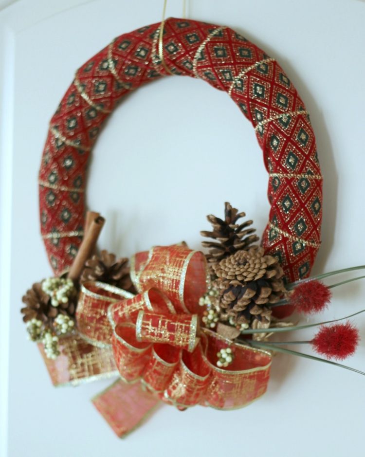 Veniec do dverí vyrobený z prírodných materiálov v červenej a zlatej farbe dverový veniec z prírodných materiálov červená stužka suché kvety šišky slučka