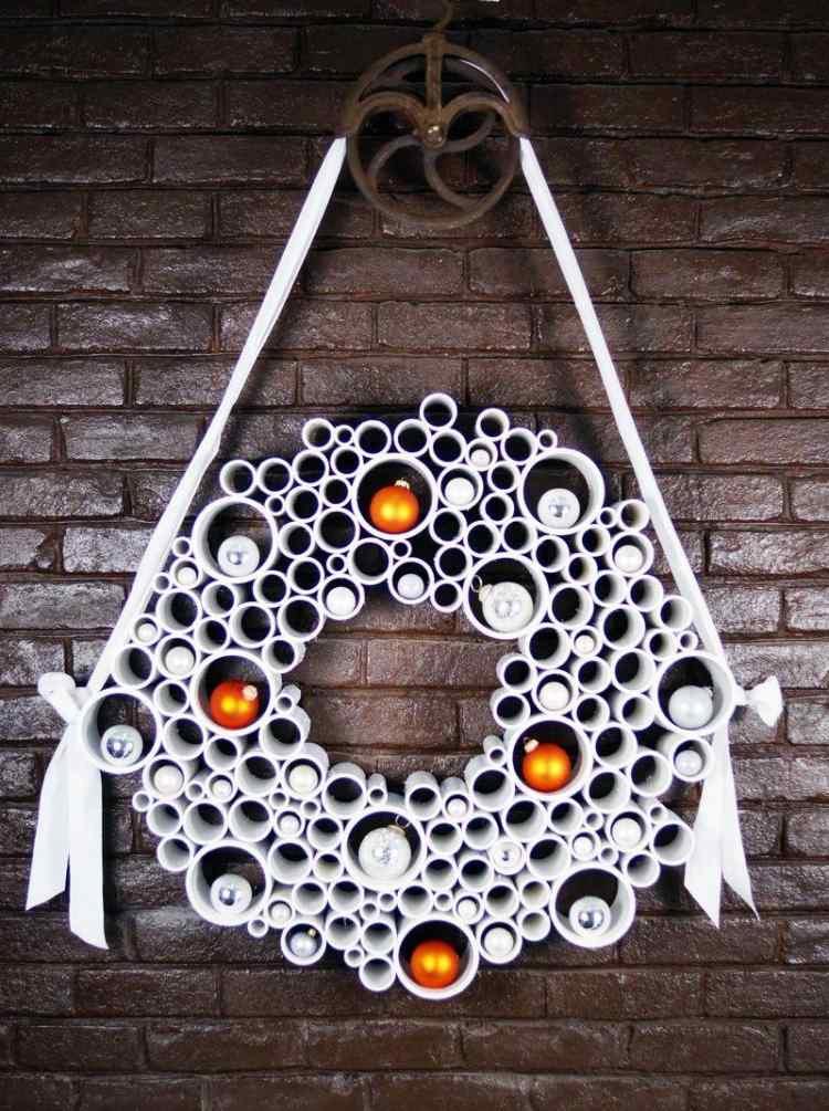 abstraktný moderný dverný veniec vyrobený z fajok v bielej farbe dverový veniec-vianočný-drotár-nápady-rúrky-biele-vianočné gule-žltá-tehlová stena