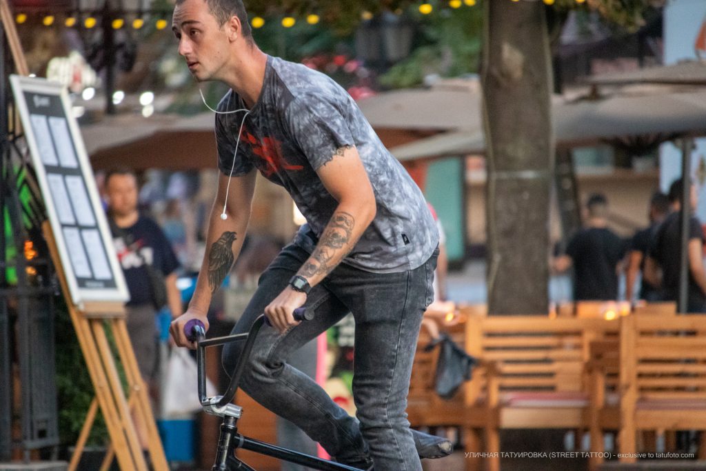 Tatuaż z czarnym krukiem i czterema czaszkami na ramionach faceta na rowerze - 17.09.2020 - 5