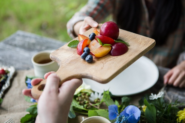 Ovocie ako slivky a čučoriedky podávajte na drevenej doske a ponúkajte ich vegánom
