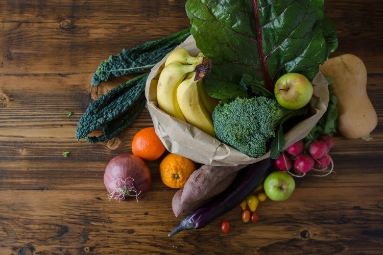 Rôzne ovocie a zelenina, ako sú banány, pomaranče, jablká, brokolica, cherry paradajky, baklažán, listová zelenina a sladké zemiaky
