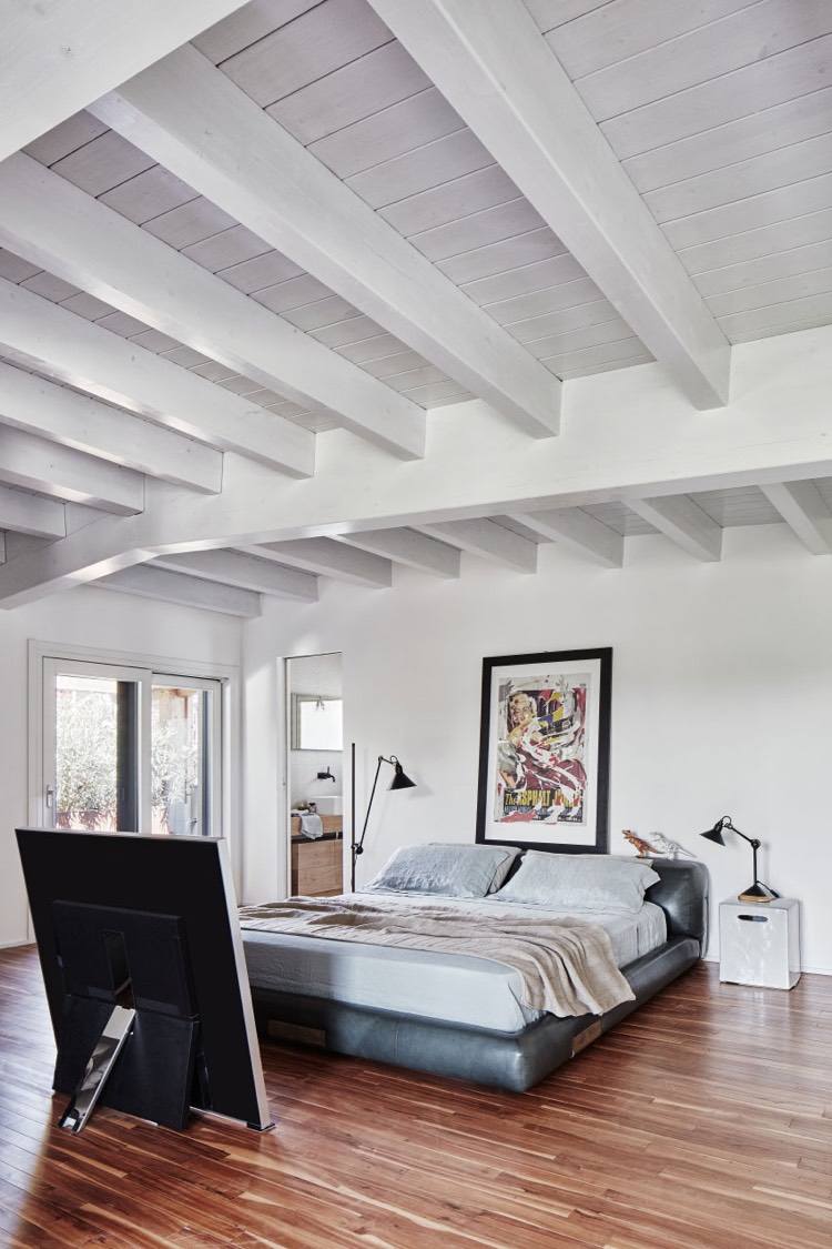 spálňa-kožená posteľ-bielo-drevené stropné trámy