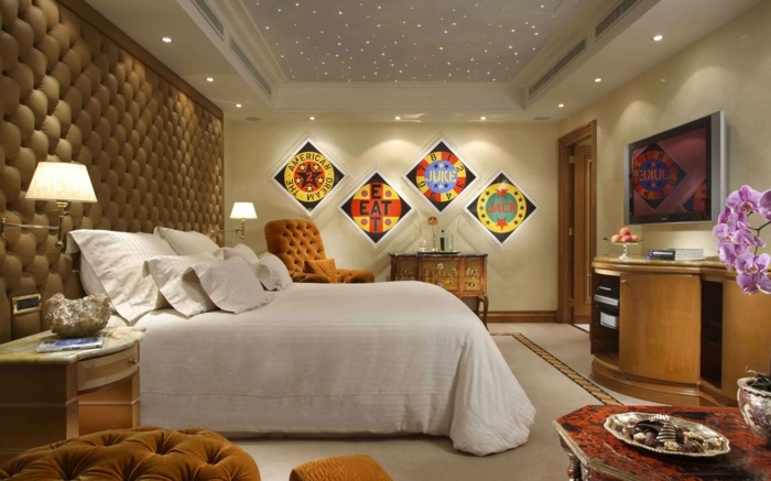 Prešívané čalúnenie sa v tejto spálni vyskytuje niekoľkokrát stenové panely s čalúnením béžová spálňová posteľ