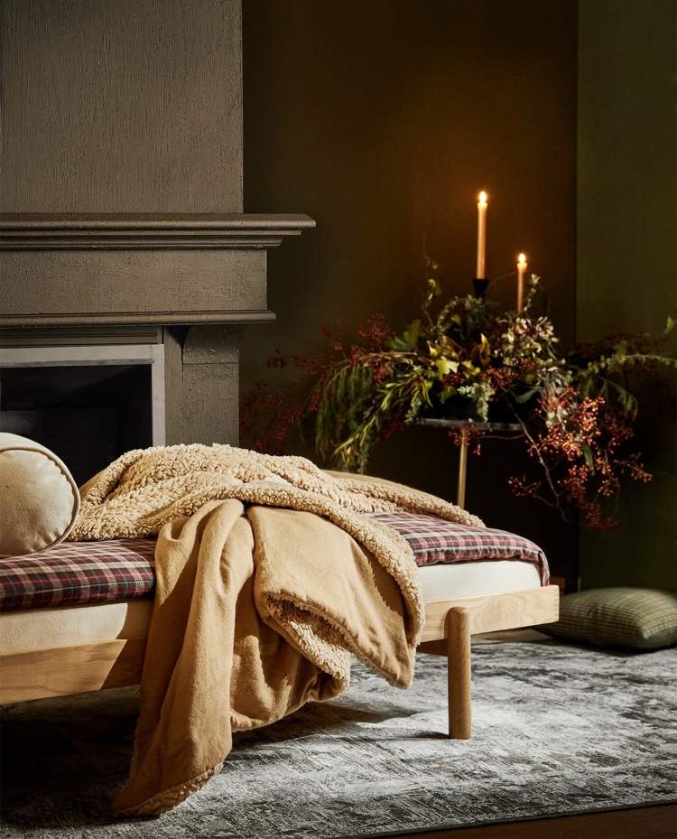 Denná posteľ v štýle vianočnej chaty s károvanou perinou a svietnikom s jedľovými ratolesťami