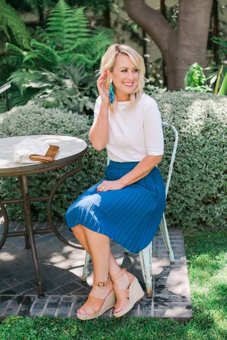 v lete oblečená do modrej skladanej sukne s klinmi