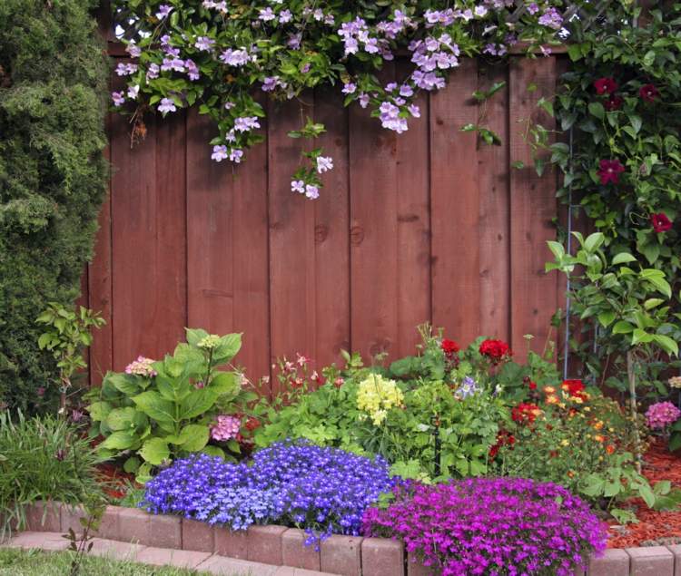 Myšlienka dreveného plotu Plot pre záhradu hnedo-drevené lamely-zemný kryt-pekná výsadba