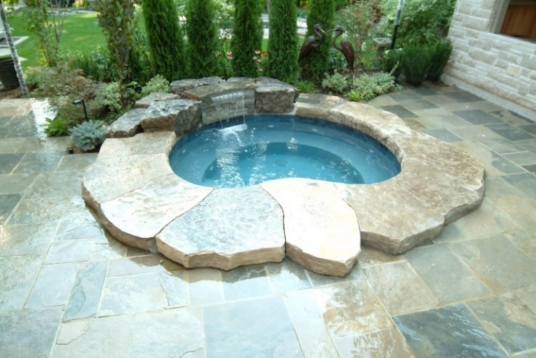 Jacuzzi obklopená kameňmi a chránená cyprusmi Záhradný kameň Whirlpool cyprus prírodný kameň