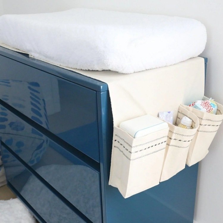 Vytvorte modernú prebaľovaciu miestnosť s tmavomodrým príborníkom s vysokým leskom a vreckami na príslušenstvo