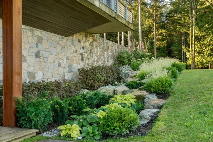 Pekná posteľ do moderného domu s nízkymi kríkmi a kameňmi