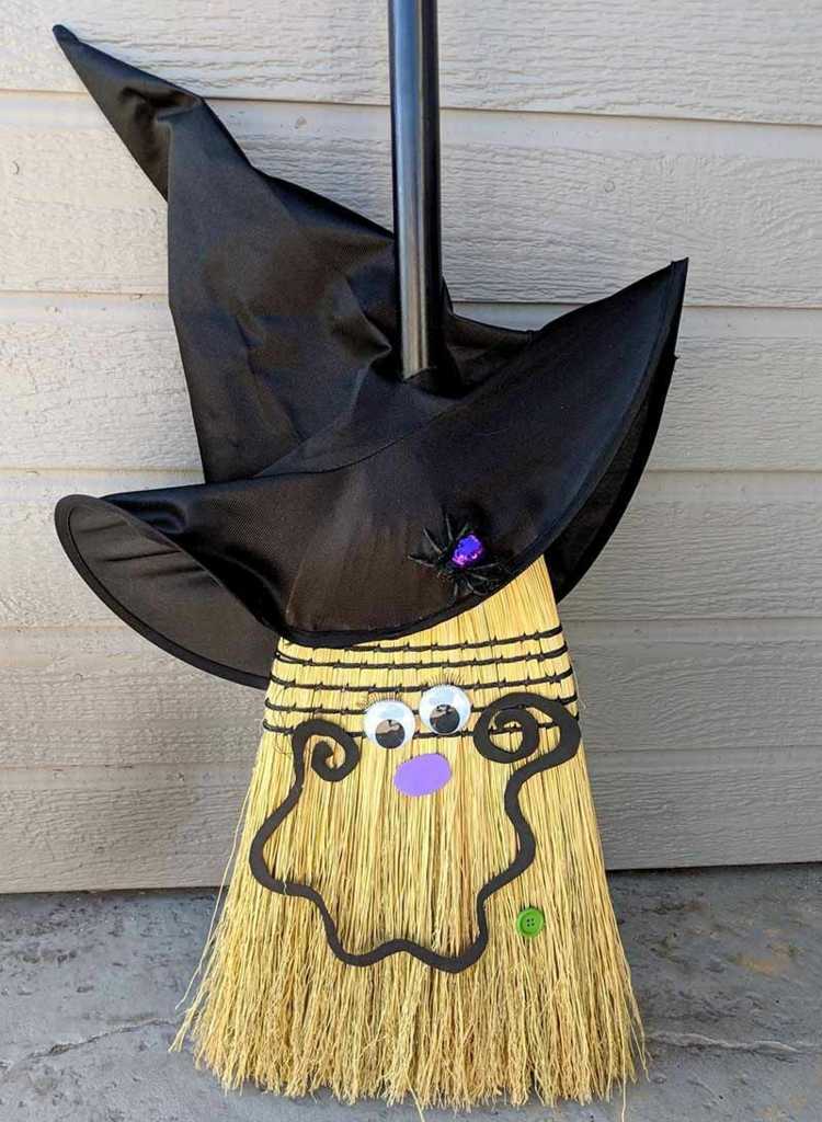 Vtipná dekorácia na Halloween s tvárou na metle a čarodejníckom klobúku