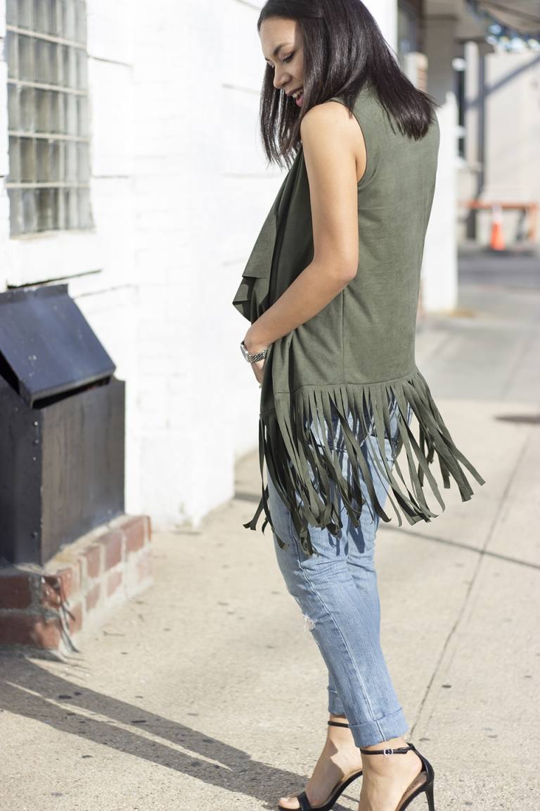 Vesta s okrajmi kombinuje úzke modré rifle na vysokom podpätku so sandálmi a módnymi trendmi pre ženy