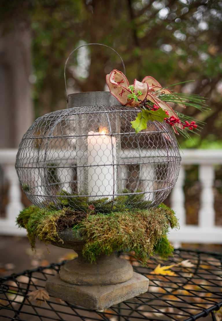 Zimná dekorácia ozdobí záhradnú lampu šípkou, mašľou a machom