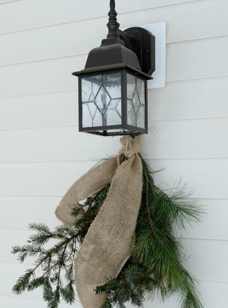 Zimná dekorácia mimo lampáša s jedľovými konármi zdobí nápad na rustikálnu výzdobu vchodu do domu